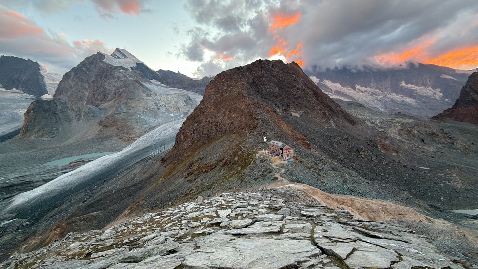 Alpine ridge and glacier beneath colourful clouds