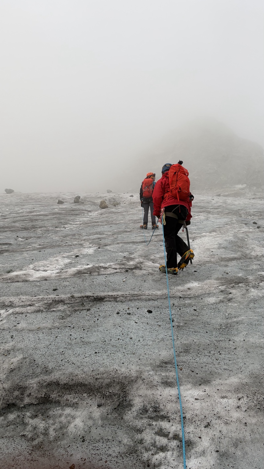 Two climbers roped together on a glacier in thick mist