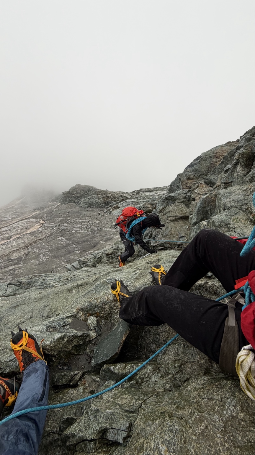 Climbers making their way across rocky terrain in mist